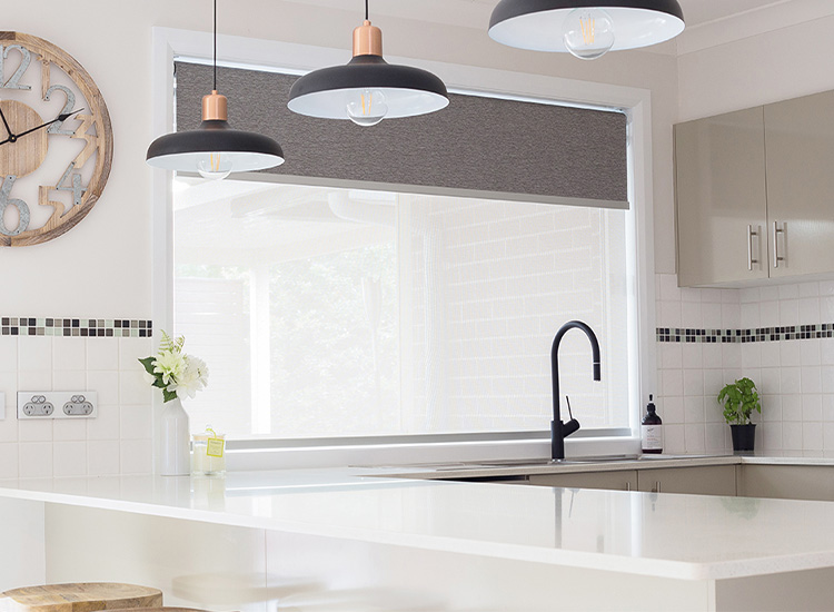 Kitchen with pendant lights and double motorised roller blinds on the window behind the sink.
