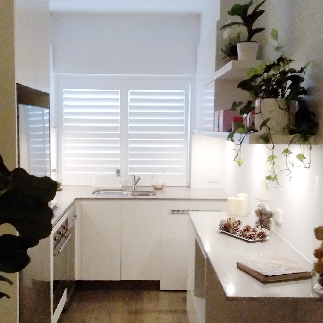 Small kitchen with a white plantation shutter above the sink.