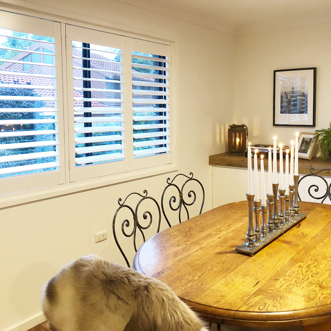 Traditional dining room with a 3 panel white plantation shutter on the window.