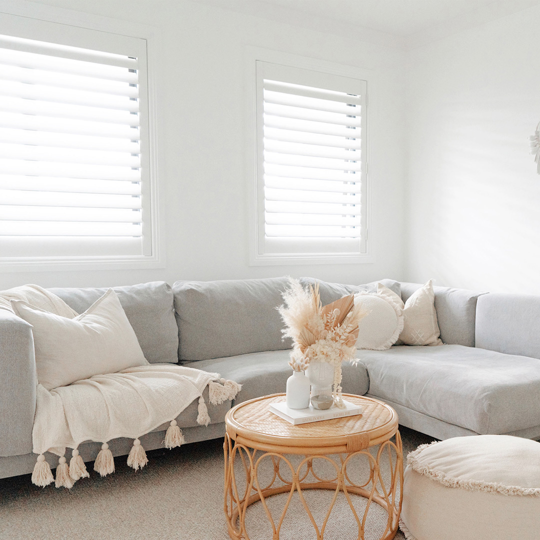 Beautiful photo of a neutral styled living room with white plantation shutters on the windows