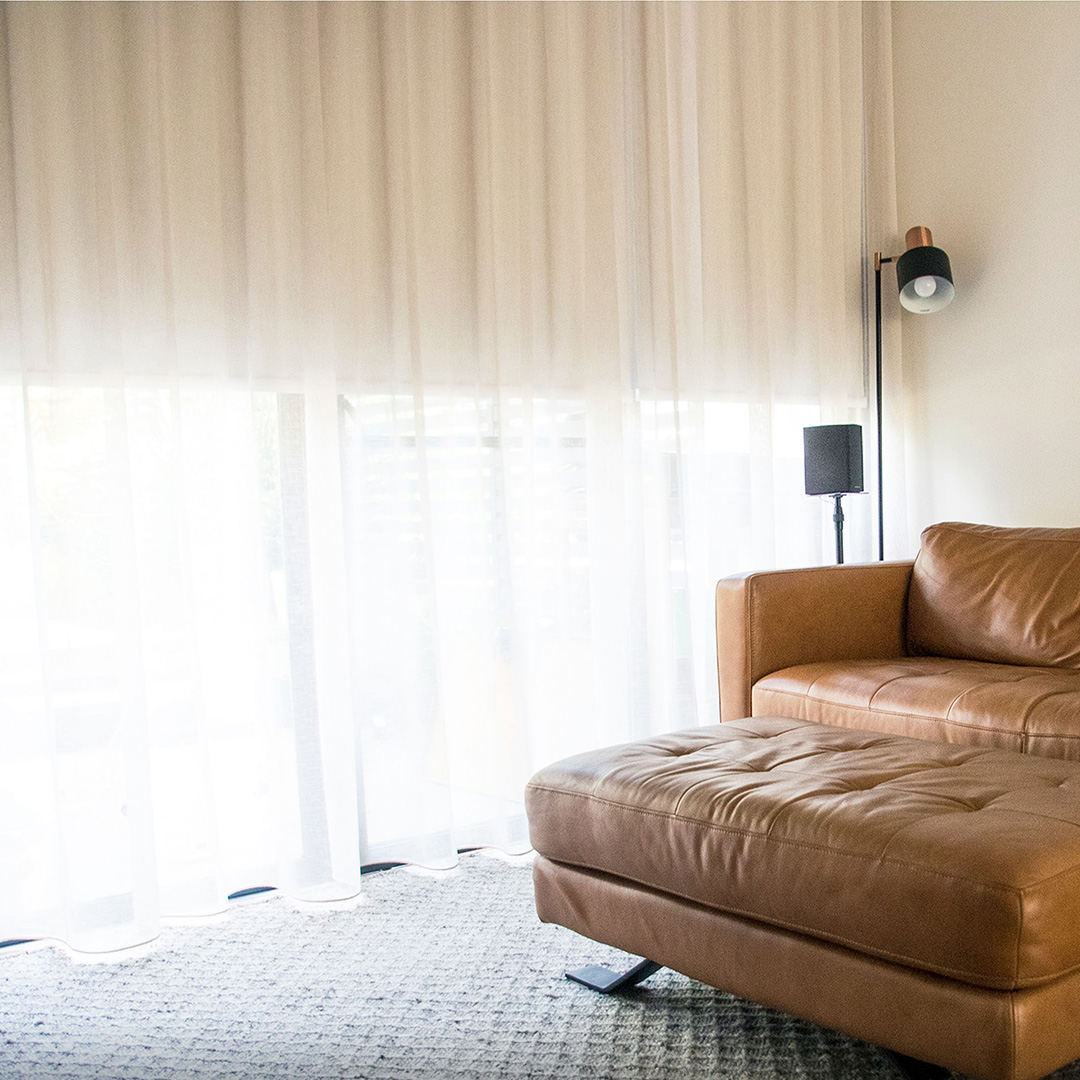 Beautiful sheer curtains in a cosy living room with a modern leather sofa. 