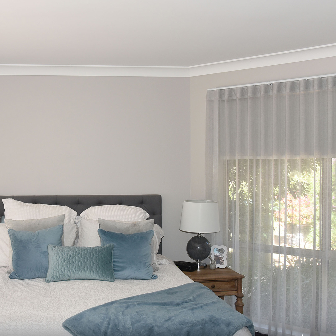 Master bedroom with light grey sheer curtains and blockout roller blinds behind. 