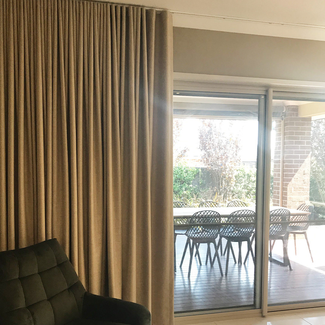Living room sliding doors featuring taupe blockout curtains looking out to an alfresco dining area. 