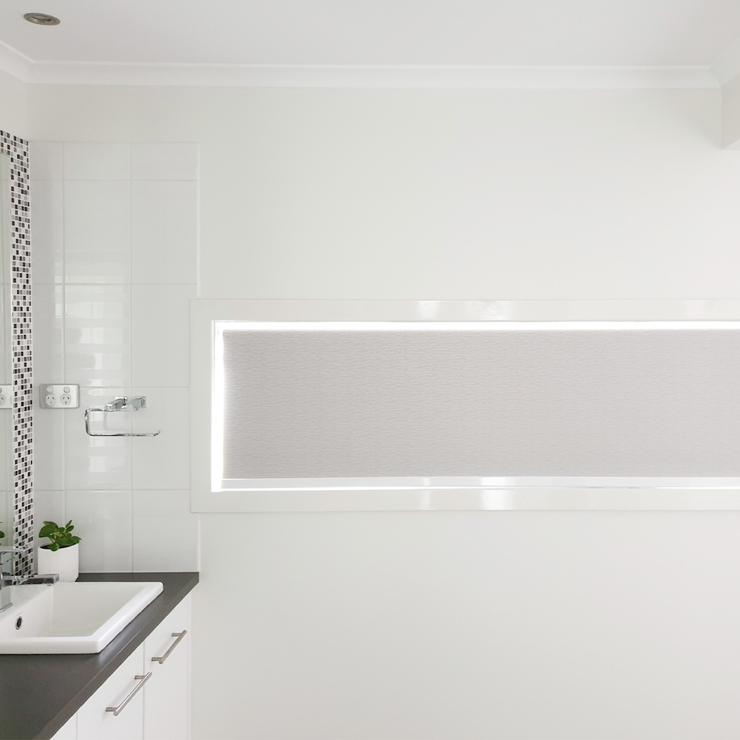 Light Grey double motorised roller blinds on a highlight window in a beautiful white bathroom.