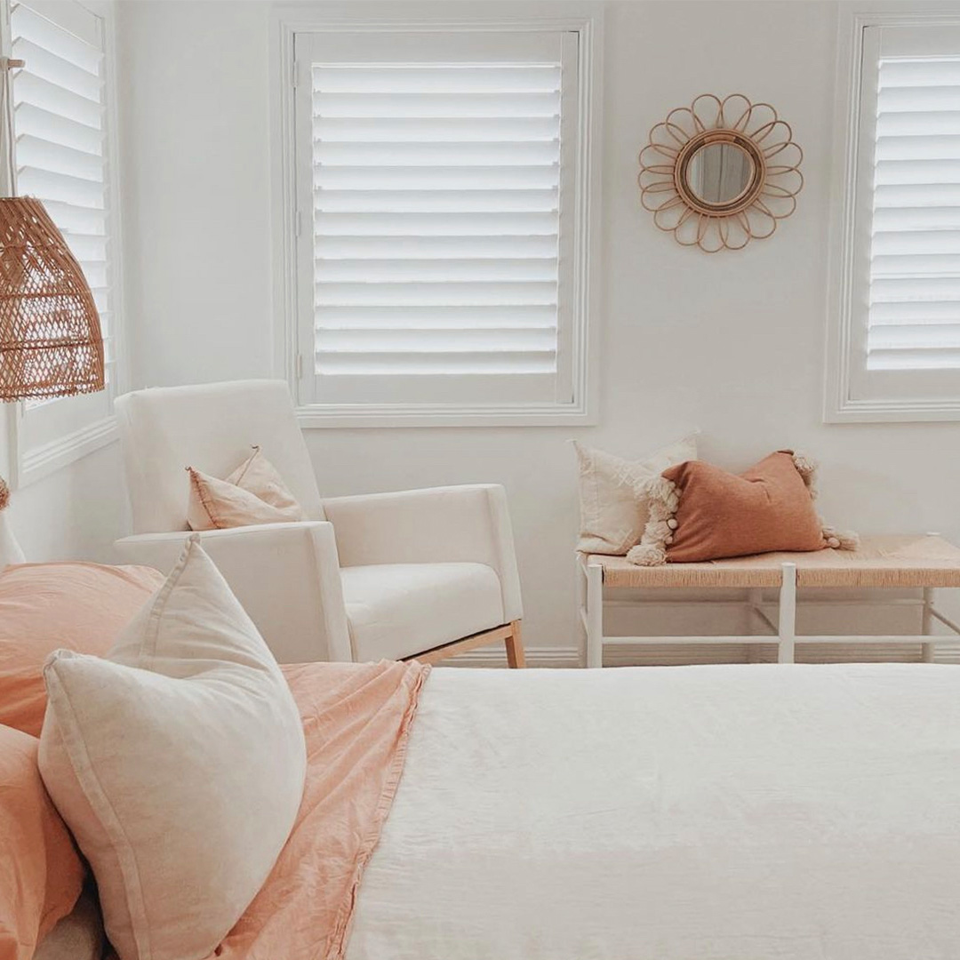 Beautiful photo of a neutral styled bedroom with white plantation shutters on the windows