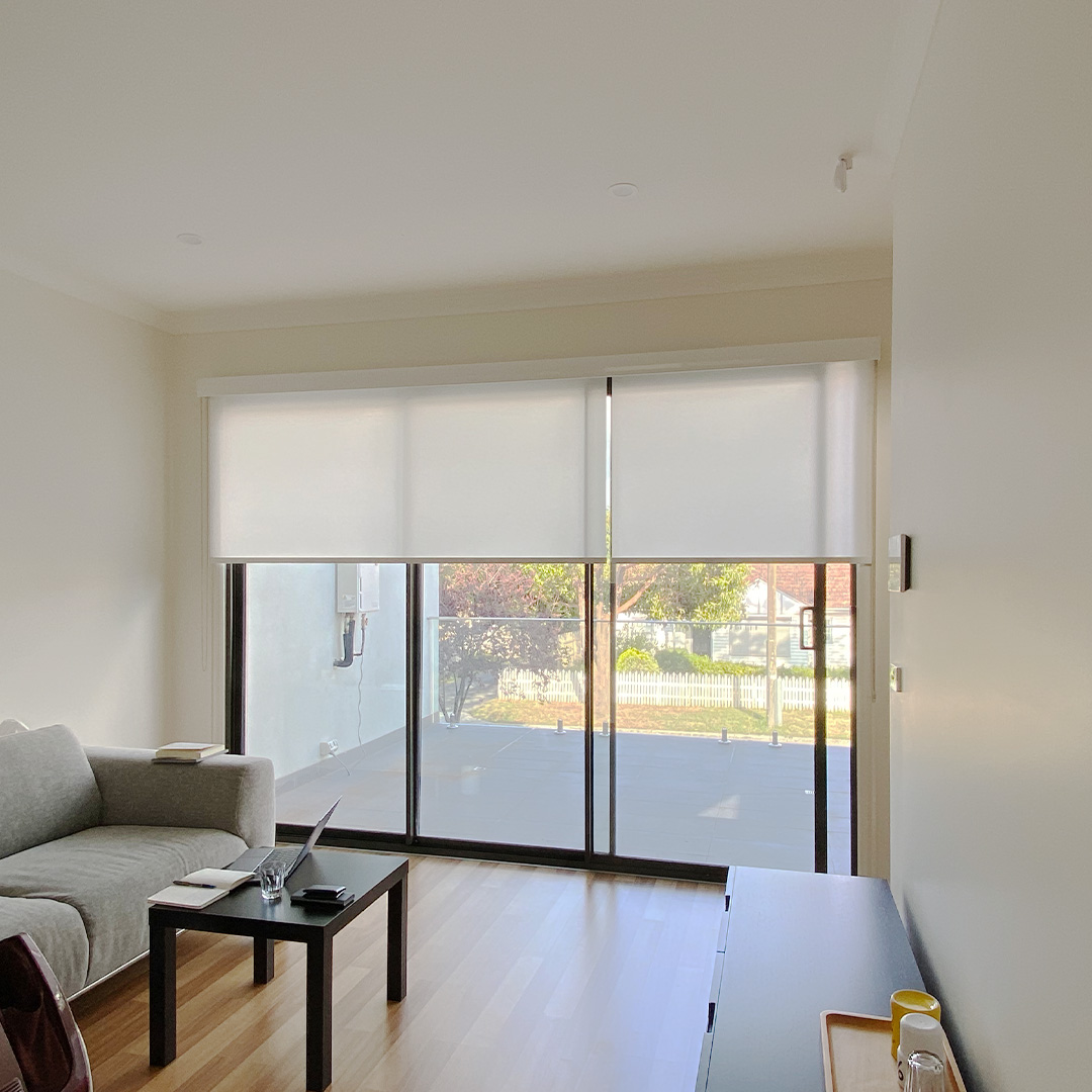 White light filter, linked roller blinds on an apartment sliding door, opening out to a balcony. 