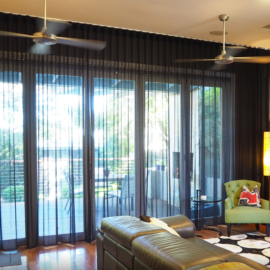 Black sheer curtains installed on the french doors of an eclectic living room. 