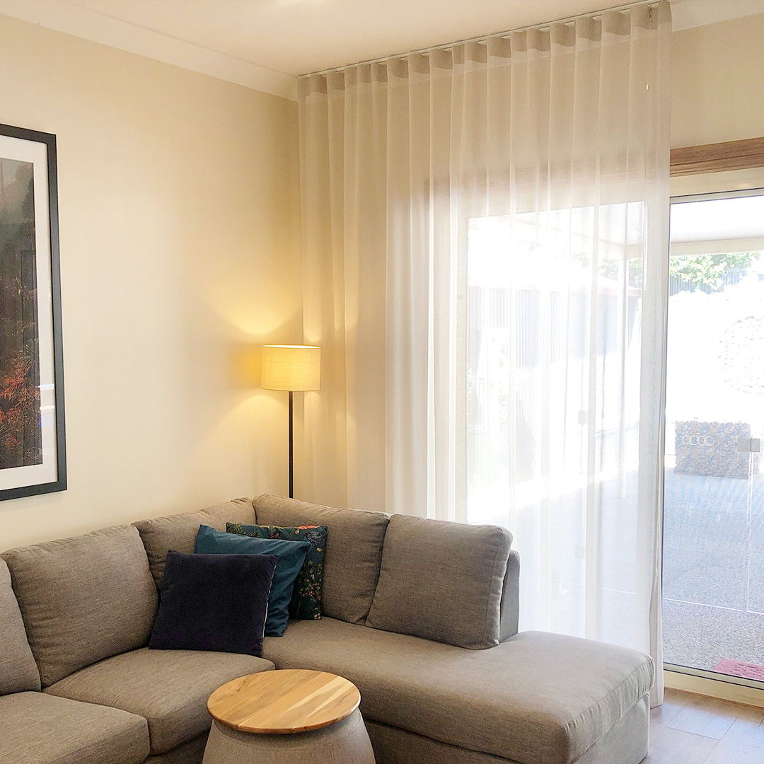 Neutral sheer curtains installed on the sliding door of a cosy living room. 