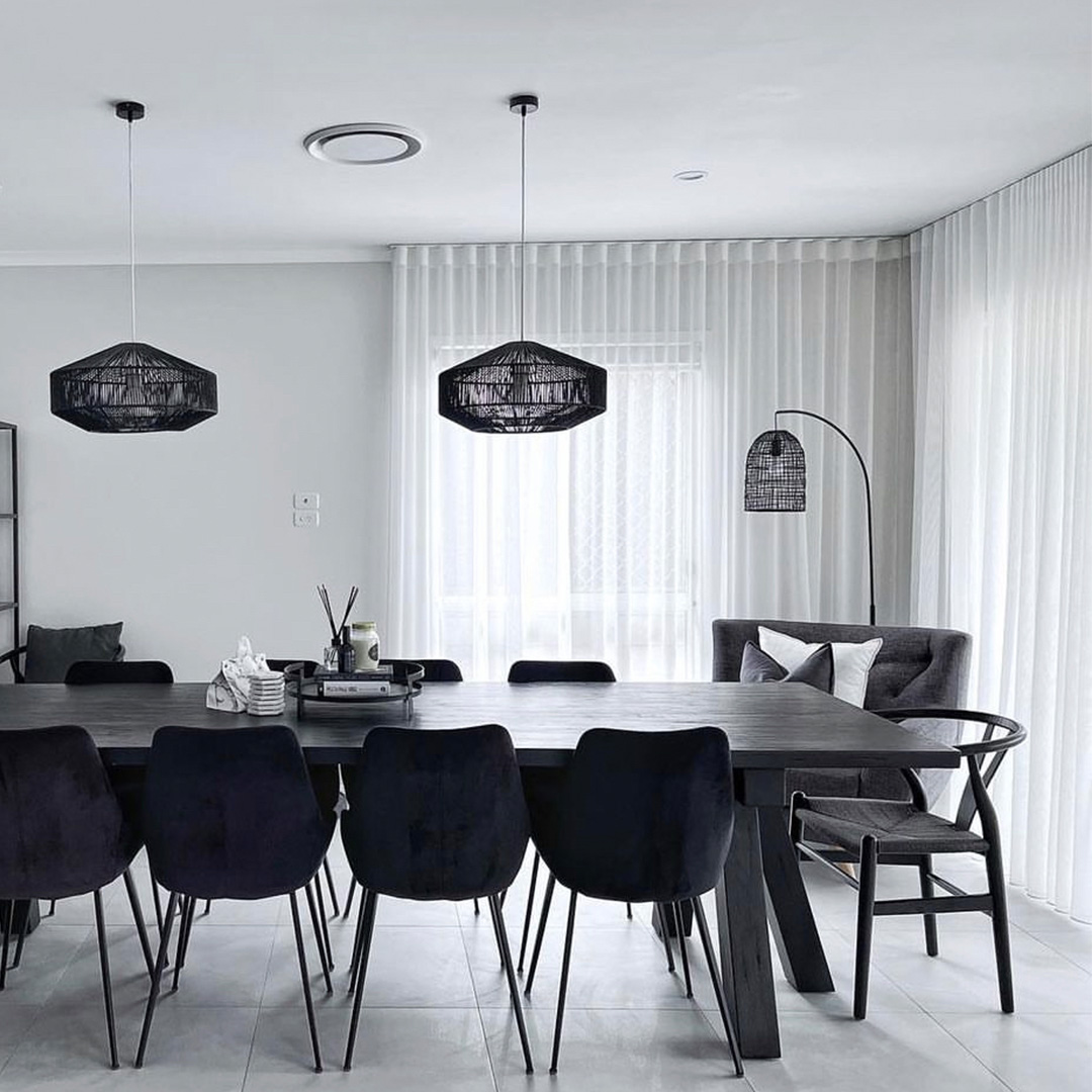 Modern, monochrome dining room with white sheer curtains on the corner windows.