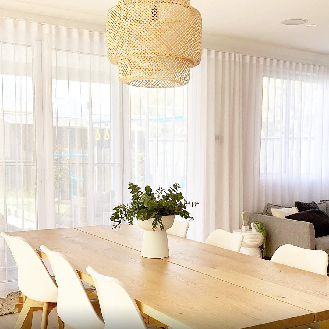 Beautiful white sheer curtains along with wall of a dining room to the living room. 