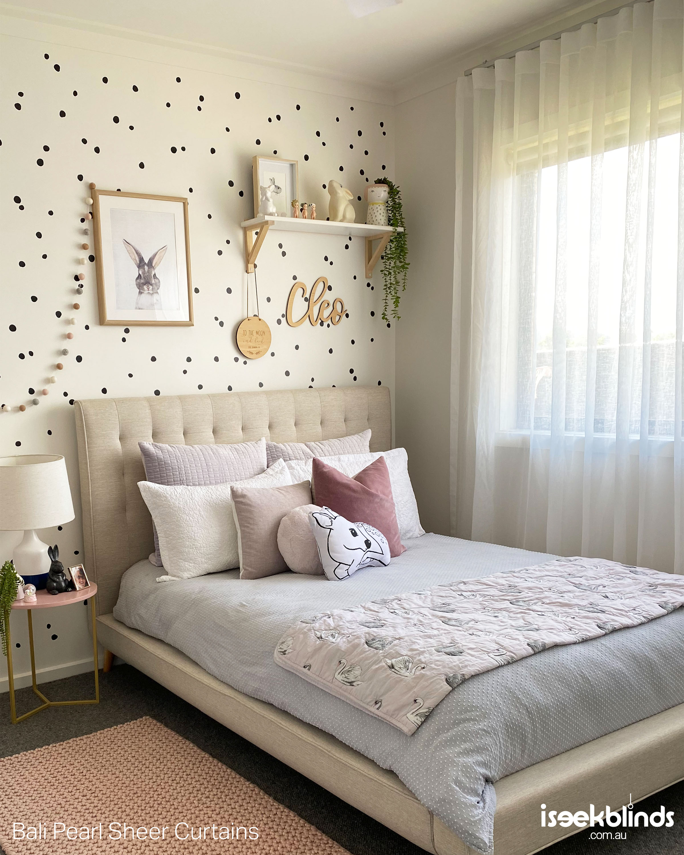 A beautifully styled young girls bedroom with white sheer curtains on the window. 