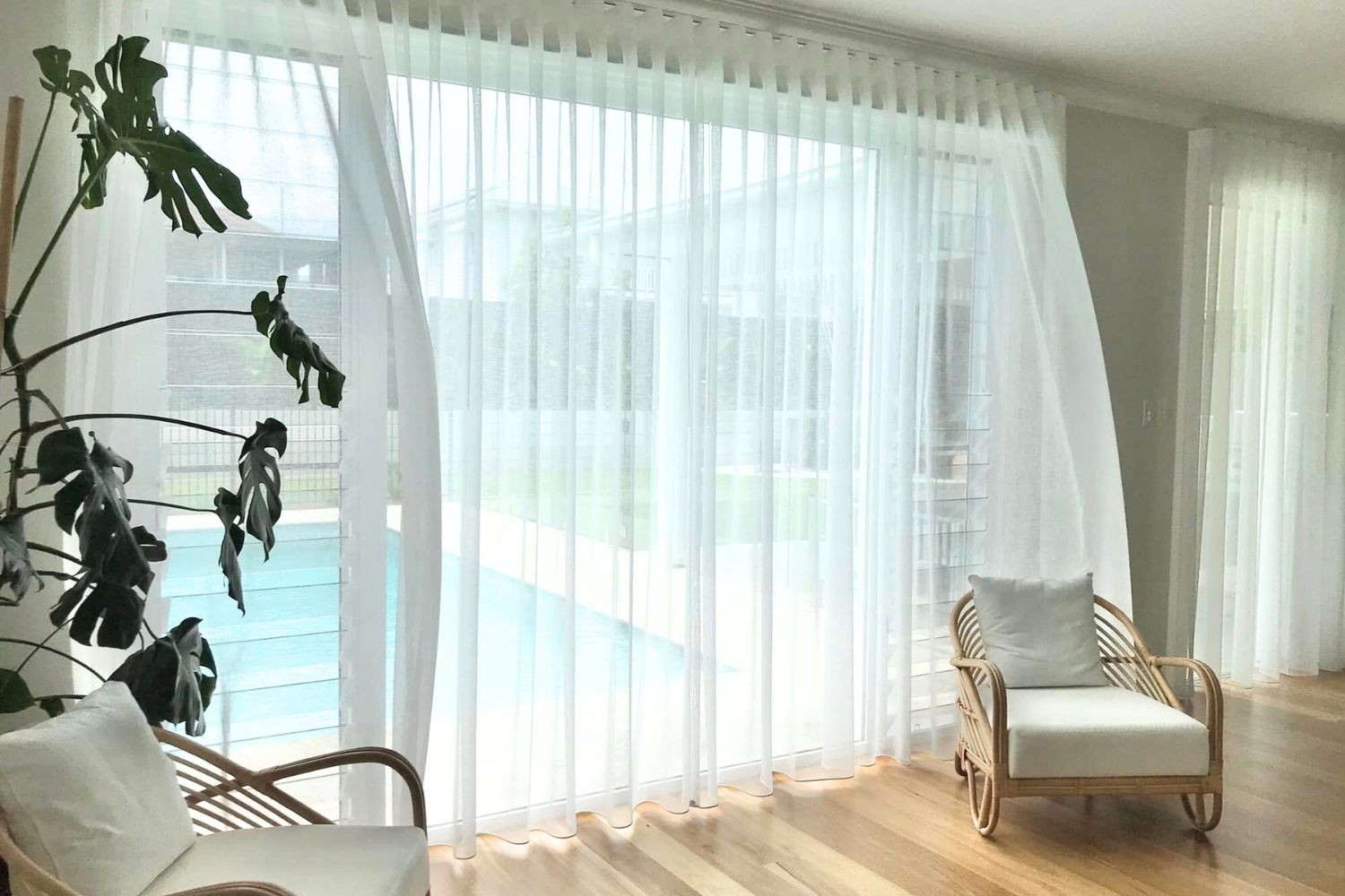 Flowing sheer curtains with view to sunnuy days and a pool outside