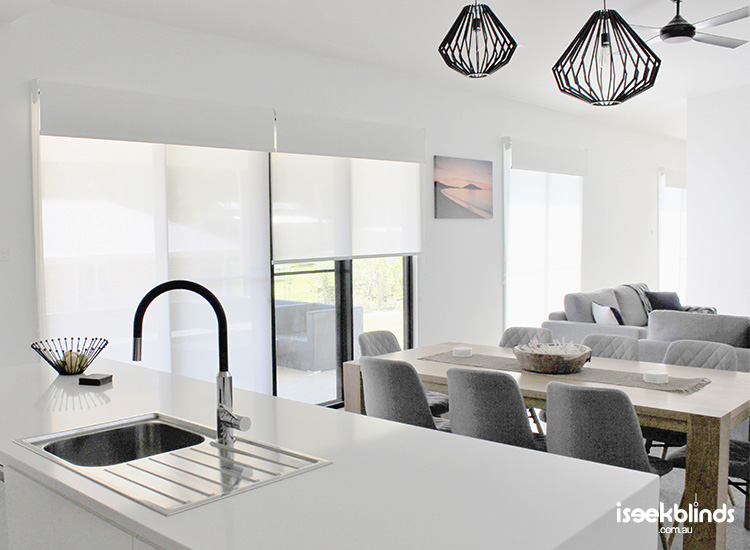 A contemporary and light filled open plan kitchen, dining and living space featuring double roller blinds from iSeekBlinds.