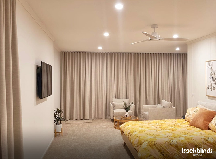 Luxurious and cost master bedroom with beige coloured blockout curtains on the end wall.