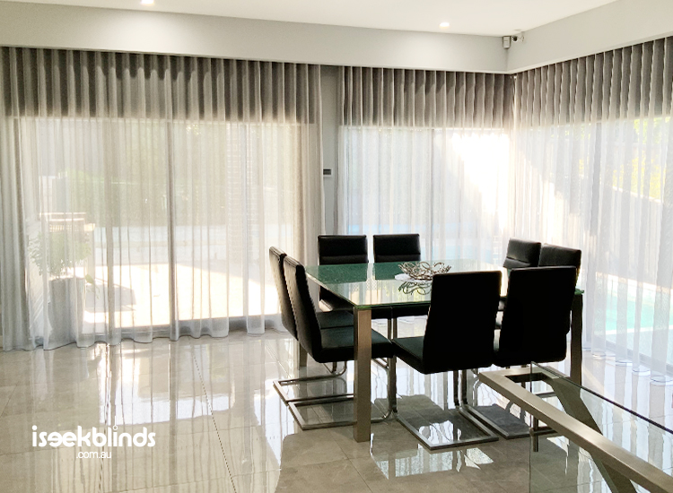 Sleek and modern dining room featuring light grey sheer curtains with roller blinds behind them.